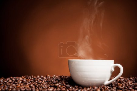 Foto de Taza de café al vapor en granos de café en la foto de cerca. Bebida refrescante por la mañana - Imagen libre de derechos