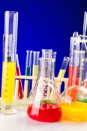 Photo for Colored liquid in chemistry set on a table over blue background. Glassware and biology equipment - Royalty Free Image