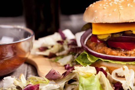 Foto de Primer plano de Deliciosa hamburguesa casera en plato de madera junto a papas fritas. Comida rápida. Snack malsano - Imagen libre de derechos