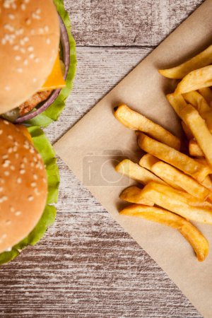 Téléchargez les photos : Delicious home made cheeseburgers on wooden plate next to fries. Fast food. Unhealthy snack - en image libre de droit
