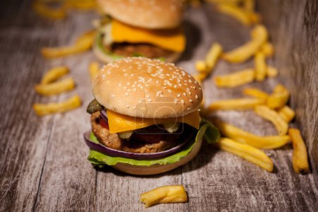 Téléchargez les photos : Classic home made burgers on wooden plate next to fries. Fast food. Unhealthy snack - en image libre de droit