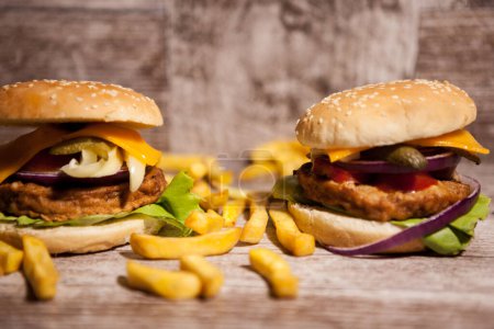 Photo for Delicious home made sandwich burgers on wooden plate next to fries. Fast food. Unhealthy snack - Royalty Free Image