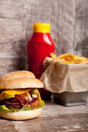 Photo for Delicious home made cheeseburgers on wooden plate next to fries. Fast food. Unhealthy snack - Royalty Free Image
