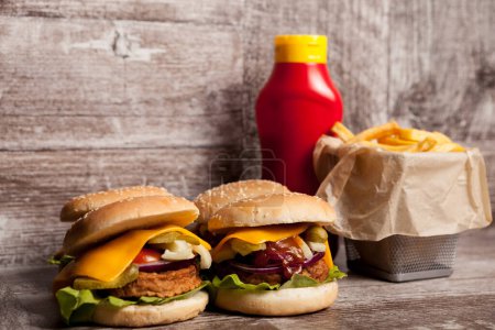 Téléchargez les photos : Délicieux cheeseburgers faits maison sur une assiette en bois à côté des frites. Restauration rapide. Collation malsaine - en image libre de droit
