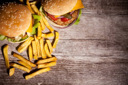 Téléchargez les photos : Classic cheeseburgers on wooden plate next to fries. Fast food. Unhealthy snack - en image libre de droit