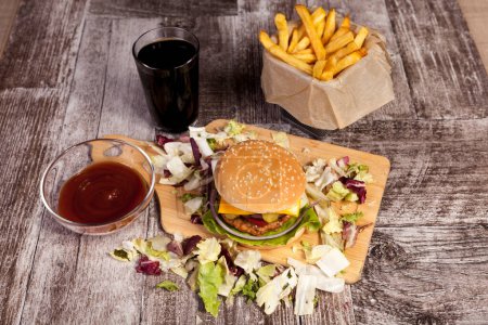 Téléchargez les photos : Délicieux hamburger sur assiette en bois à côté des frites. Restauration rapide. Collation malsaine - en image libre de droit