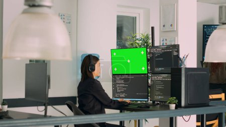 Téléchargez les photos : Asian system engineer programming app code on monitors with greenscreen template and terminal window. Asian coder working with chromakey template and isolated mockup on multiple screens. - en image libre de droit