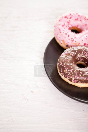 Photo for Close up of delicious donuts in black plate - Royalty Free Image