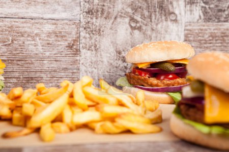 Photo for Tasty home made burgers on wooden plate next to fries. Fast food. Unhealthy snack - Royalty Free Image