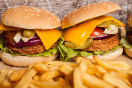 Téléchargez les photos : Tasty home made cheeseburgers on wooden plate next to fries. Fast food. Unhealthy snack - en image libre de droit