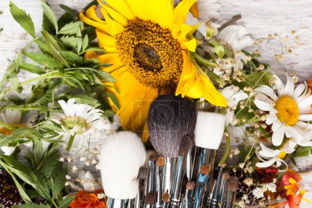 Téléchargez les photos : Accessoires de maquillage à côté de fleurs sauvages sur fond en bois - en image libre de droit