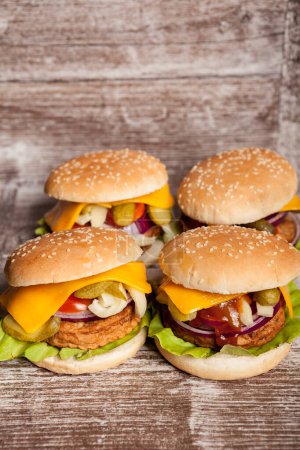 Téléchargez les photos : Quatre délicieux hamburgers faits maison sur une assiette en bois. Restauration rapide. Collation malsaine - en image libre de droit