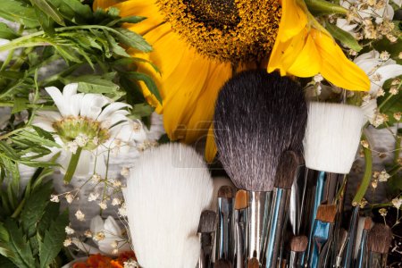 Foto de Make up accessories next to wild flowers on wooden background - Imagen libre de derechos