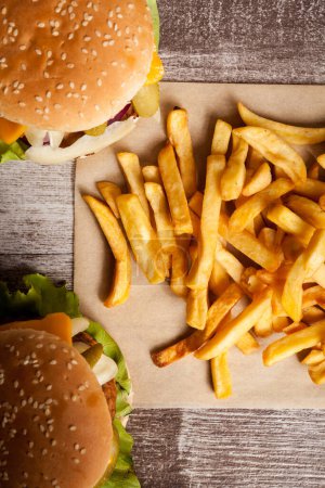 Téléchargez les photos : Home made cheeseburgers on wooden plate next to fries. Fast food. Unhealthy snack - en image libre de droit