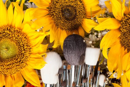 Téléchargez les photos : Make up brushes next to beautiful wild flowers on wooden background - en image libre de droit