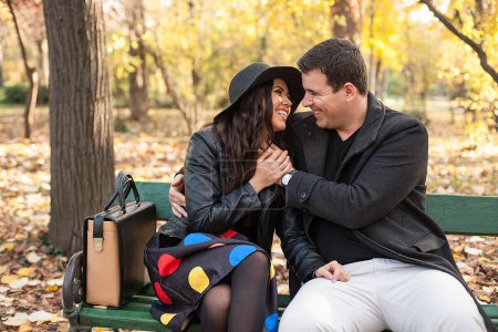 Foto de En el amor feliz joven pareja sentada en un banco en el parque de otoño - Imagen libre de derechos