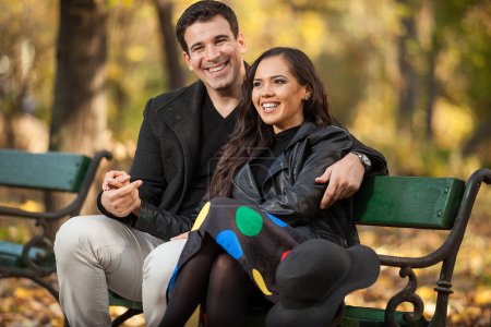 Téléchargez les photos : Joyeux couple assis sur un banc dans le parc d'automne - en image libre de droit