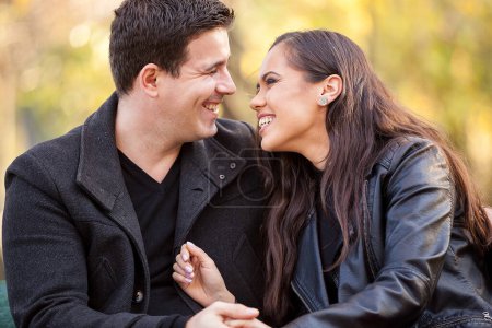 Photo for Close up of happy beautiful in love couple sitting on a bench in autumn park - Royalty Free Image