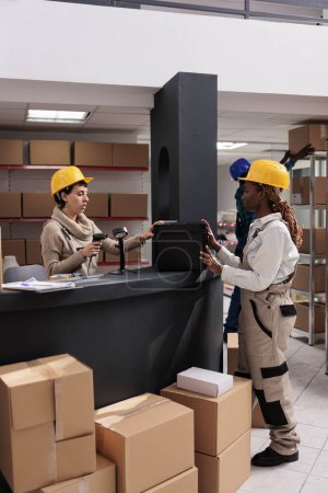 Photo for Warehouse manager scanning black case at counter desk and doing inventory. Industrial storehouse coworkers checking stock supply and using barcode scanner at product at delivery office reception - Royalty Free Image