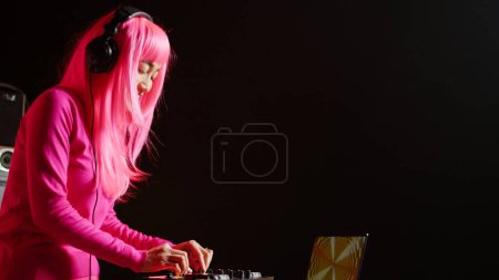 Photo for Smiling dj enjoying playing electronic song at mixer console, performing techno music in front of crowd. Asian musician doing performance at nightclub with professional audio equipment - Royalty Free Image
