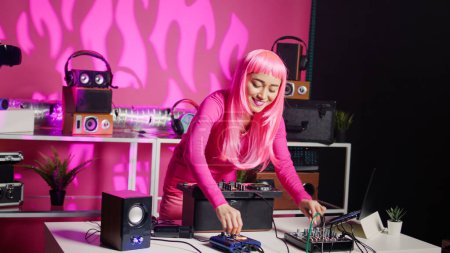 Foto de Dj performer having fun while playing electronic song at professional turntables, performing techno music in front of fans. Asian artist enjoying playing at nightclub using audio equipment - Imagen libre de derechos
