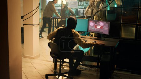 Téléchargez les photos : Skilled hacker successfully cracking security network on computer, doing hacking and espionage work at night. Male criminal being congratulated about cryptojacking achievement. - en image libre de droit