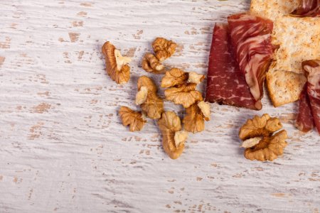 Téléchargez les photos : Jambon, noix, craquelins et raisins sur fond vintage en bois blanc en studio photo - en image libre de droit