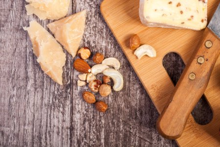 Foto de Diferentes tipos de queso y nueces sobre fondo de madera en la foto de cerca. Copyspace disponible - Imagen libre de derechos