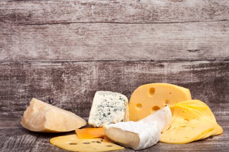 Foto de Diferentes tipos de queso sobre fondo de madera. Apetizador de alimentos gourmet - Imagen libre de derechos