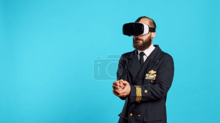 Foto de Piloto de avión usando auriculares vr con visión interactiva, divirtiéndose con gafas de realidad virtual. Capitán de aerolínea joven con uniforme aviaton utilizando gadget de simulación 3d, tripulación del aire. - Imagen libre de derechos