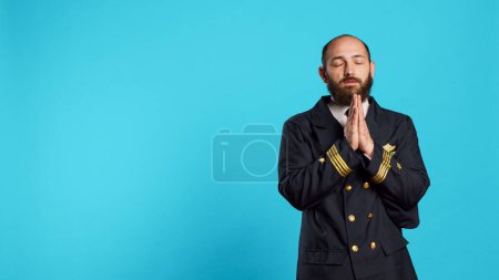 Photo for Religious young aviator praying to jesus on camera, being spiritual and worshiping god. Male airplane pilot holding hands in prayer symbol, asking for forgiveness and having faith in holy christ. - Royalty Free Image