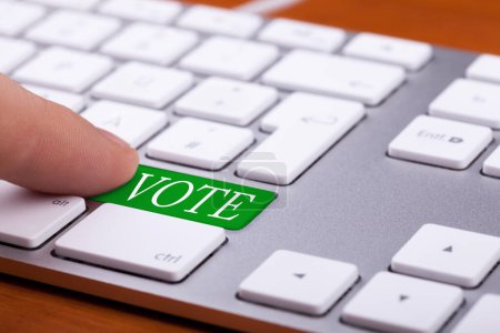 Foto de Dedo presionando el botón verde de voto en el teclado. Elecciones en línea - Imagen libre de derechos
