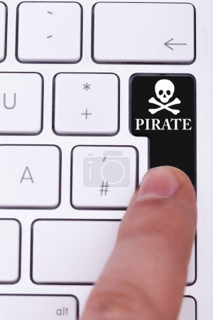 Foto de Dedo presionando el botón pirata y el cráneo en el teclado. Transferencia ilegal de datos - Imagen libre de derechos