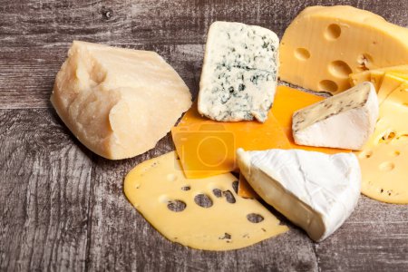 Foto de Diferentes tipos de queso sobre fondo de madera. Apetizador de alimentos gourmet - Imagen libre de derechos