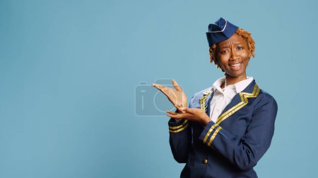 Photo for Young stewardess applauding in studio, cheering for something doing standing ovation. Excited happy model dressed as aircrew member clapping hands, having professional occupation. - Royalty Free Image