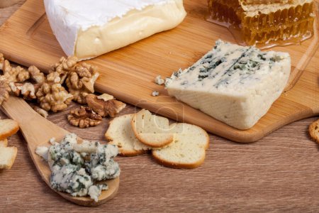 Téléchargez les photos : Différents types de fromage cher, noix et miel sur fond en bois - en image libre de droit