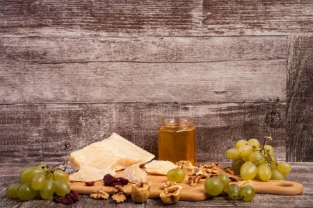 Photo for Different type of cheese, honey, grape and nuts on wooden background in studio photo - Royalty Free Image