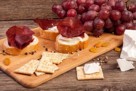 Photo for White cheese, ham and grape on wooden plate in studio photo - Royalty Free Image