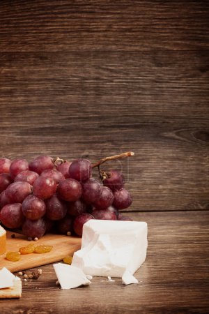 Téléchargez les photos : Fromage blanc, noix et raisin rouge sur fond bois en tonification vintage. Style de vie sain - en image libre de droit