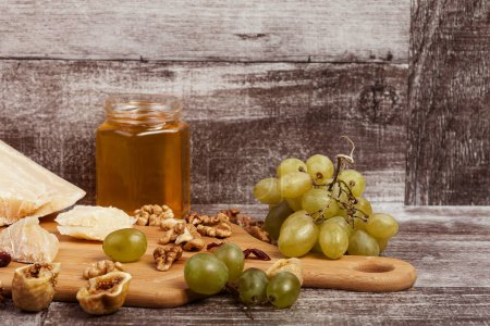 Téléchargez les photos : Parmesan, miel, noix et raisin sur fond bois en studio photo. Mode de vie sain - en image libre de droit