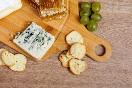 Téléchargez les photos : Vue sur le dessus de l'assiette avec noix, fromage, raisins et craquelins sur fond de bois vintage en studio photo. Mode de vie sain - en image libre de droit