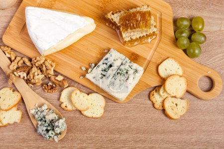 Téléchargez les photos : Vue sur le dessus de l'assiette avec noix, fromage, raisins et craquelins sur fond de bois vintage en studio photo. Mode de vie sain - en image libre de droit