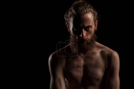 Téléchargez les photos : Portrait de hipster cool barbu sur fond noir en photo studio. Expression et mode - en image libre de droit