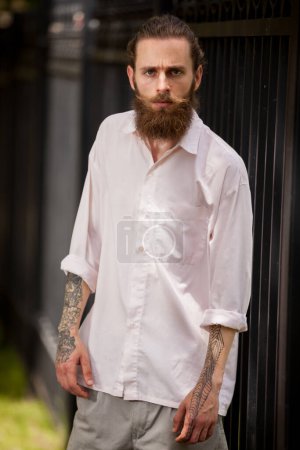 Photo for Cool looking hipster guy wih long beard posing outside in the city. Style and diversity - Royalty Free Image