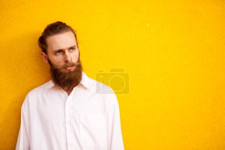 Téléchargez les photos : Tatoué barbu guy sur jaune mur posant extérieur - en image libre de droit