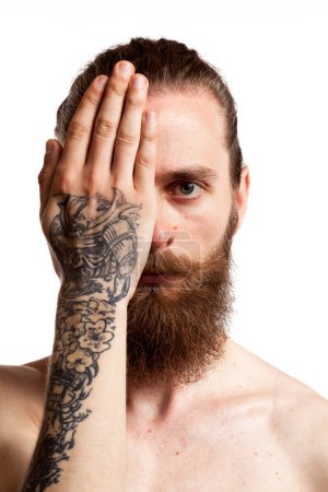 Téléchargez les photos : Cool hipster avec longue barbe et tatouages sur fond blanc en studio photo - en image libre de droit