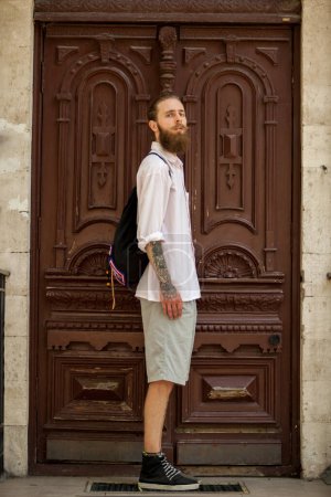 Photo for Hipster in white shirt posing in front of a door outside in the city. Style and diversity - Royalty Free Image