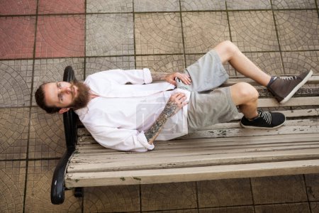 Photo for Bearded hipster lying on a bench. Style and fashion - Royalty Free Image