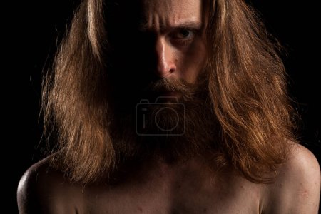 Téléchargez les photos : Hipster aux cheveux longs et barbe sur fond noiren studio photo. Expression et mode - en image libre de droit