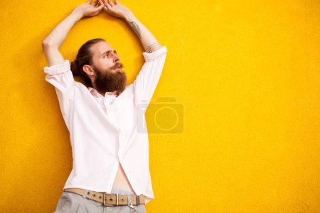 Photo for Tattooed bearded man on yellow wall posing outdoor - Royalty Free Image